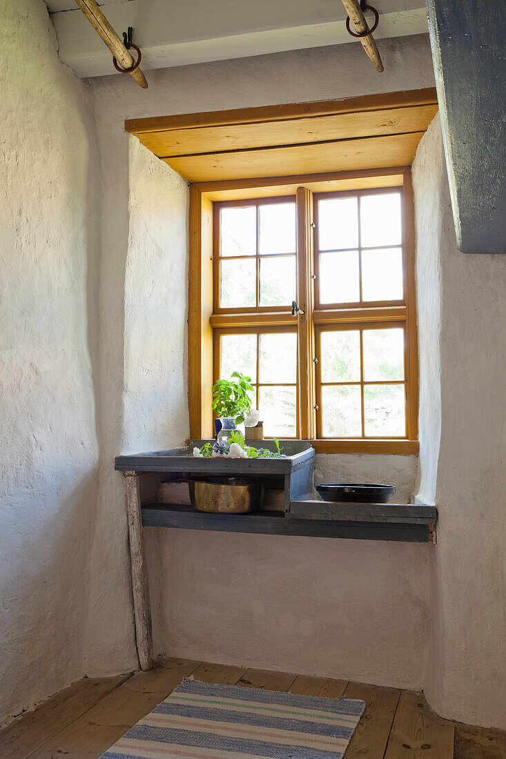 Rustic kitchen niche with small window, sink and herb pot