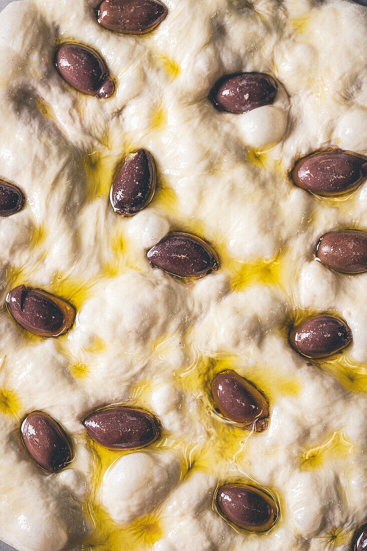 Unbaked focaccia with Kalamata olives and olive oil
