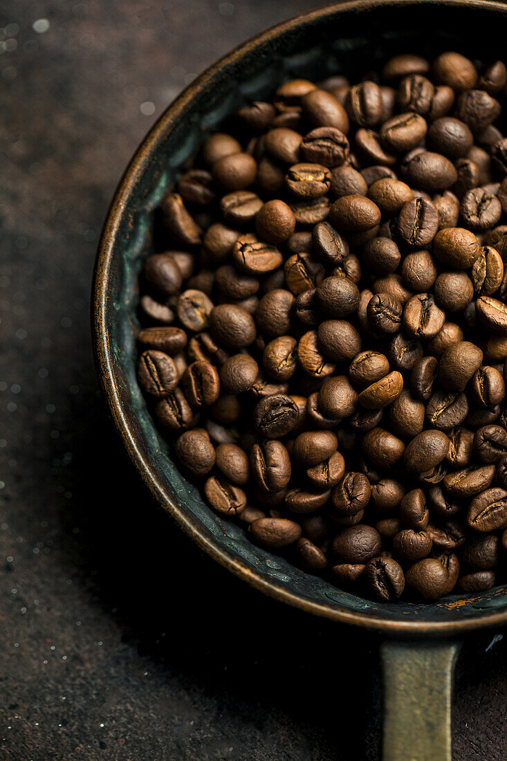 Ganze geröstete Kaffeebohnen in rustikaler Pfanne