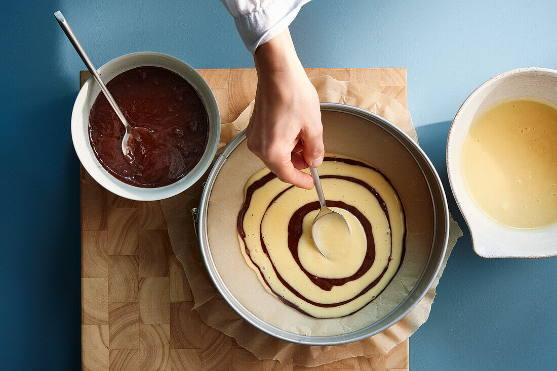 Making zebra cake - alternate spoonfuls of light and dark batter into the centre of the baking tin