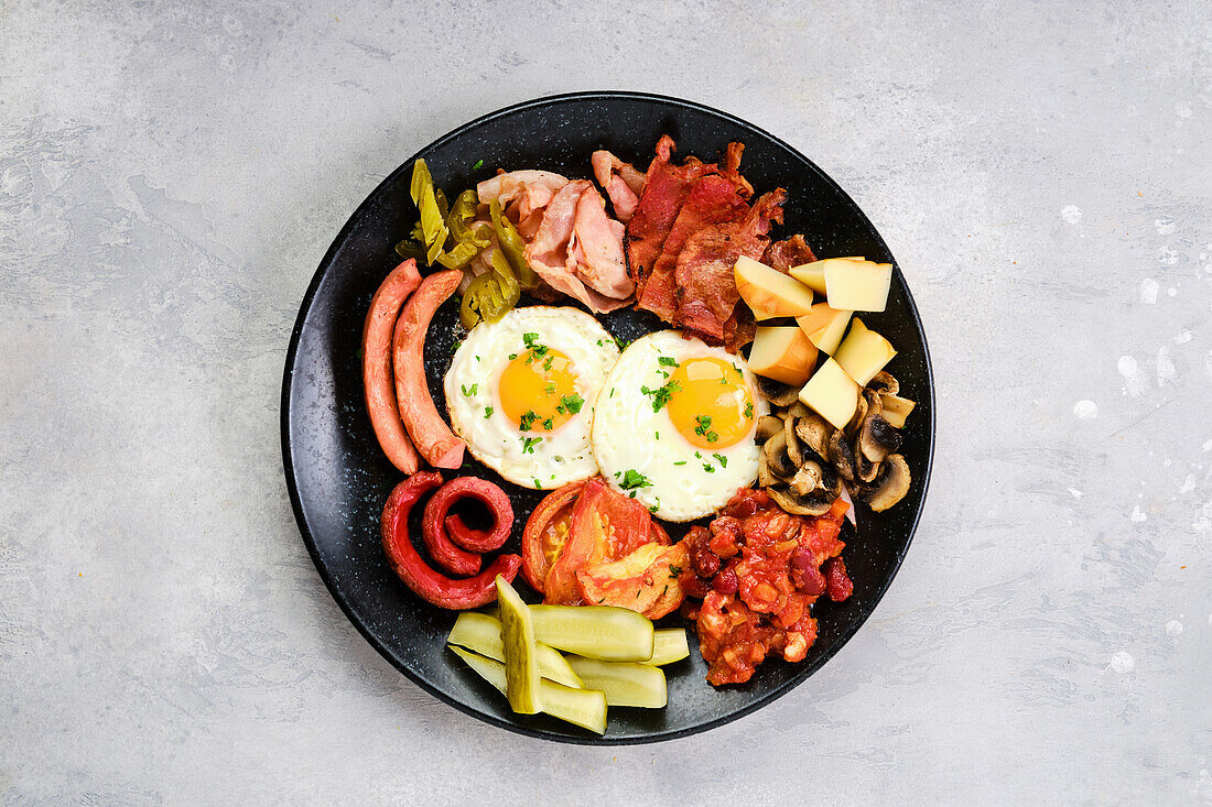 Englisches Frühstück mit Spiegeleiern, Würstchen und gebratenem Gemüse