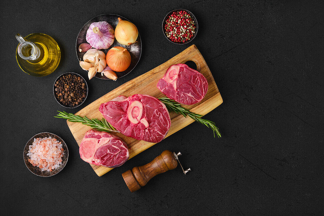 Raw ossobuco with spices and olive oil on a wooden board