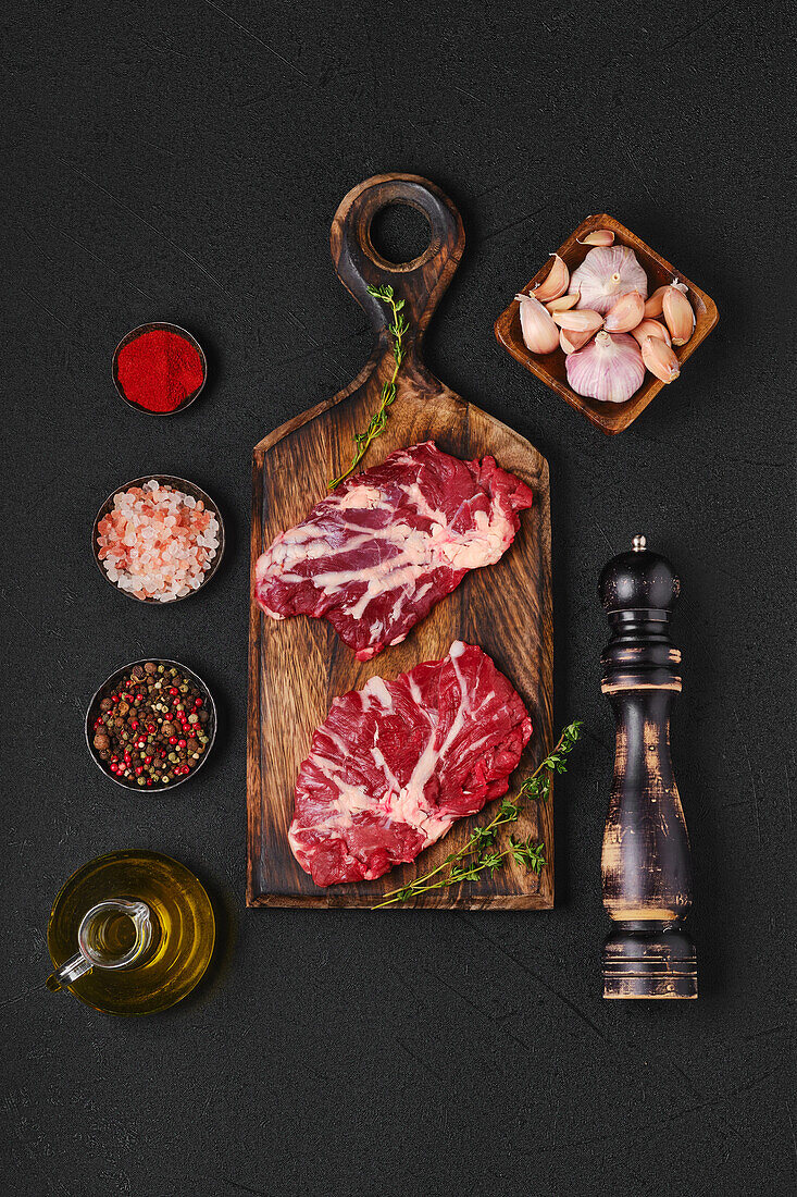 Raw beef steaks with spices on a chopping board