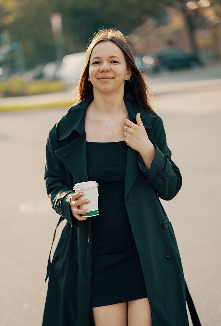 Smiling teenage girl holding cup of coffee