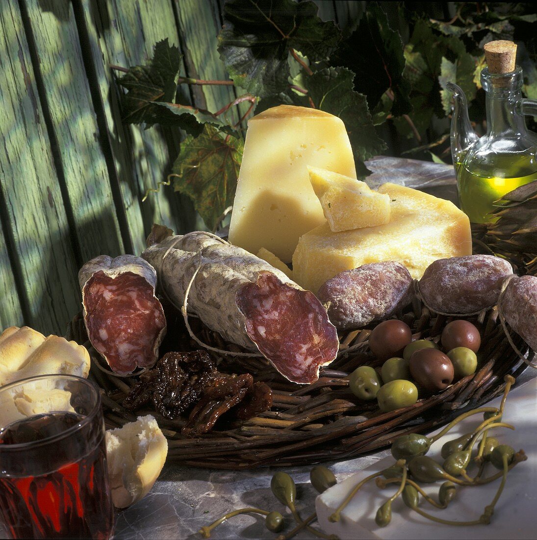 Italian still life with salami, cheese, olives, capers, wine