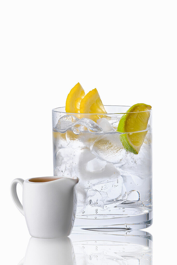 Glass with ice cubes and lemon slices; jug with espresso