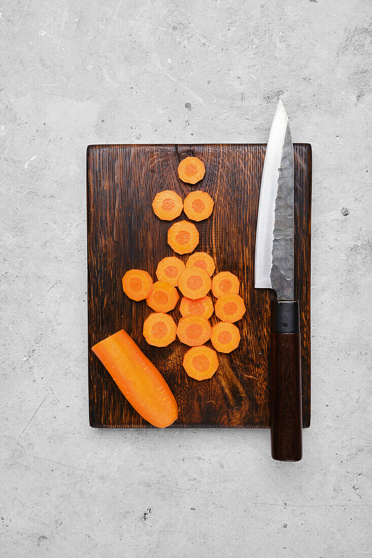 Sliced carrots on a wooden board with a knife