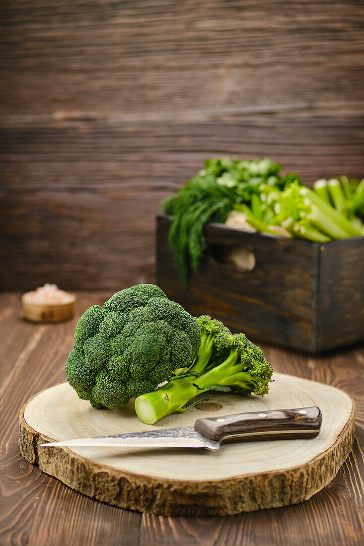 Broccoli with knife on wooden cutting board
