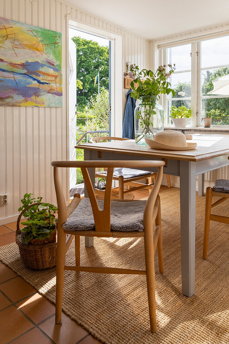 Dining area with wooden table, chairs and plants, view of the garden