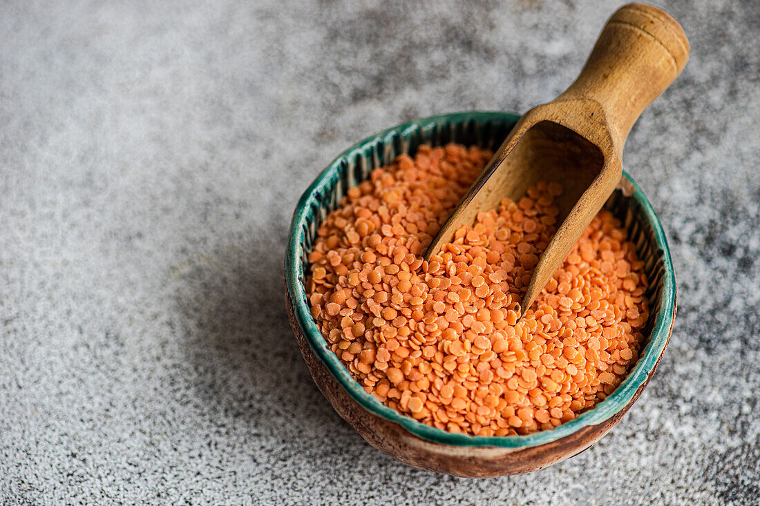 Red lentils in bowl with wooden spoon