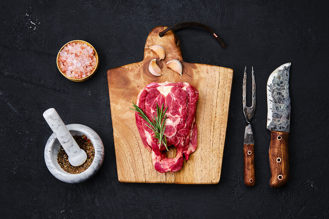 Raw lamb neck steak with herbs and spices on a wooden board