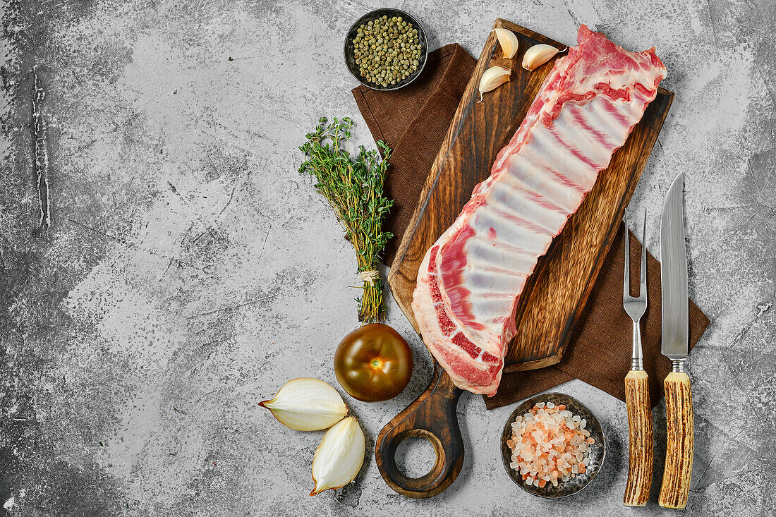 Raw lamb ribs with spices and herbs on a wooden board