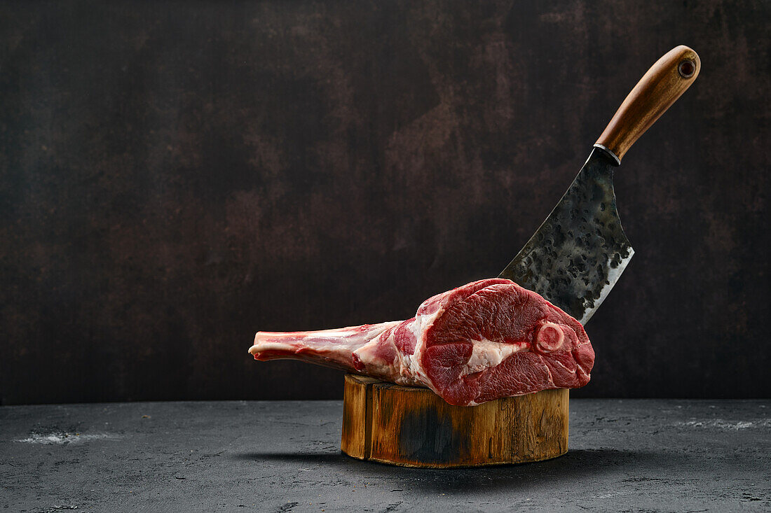 Raw leg of lamb with butcher's cleaver on wooden block