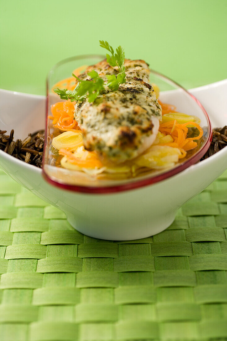 Fish fillet wrapped in herbs on a bed of vegetables with wild rice