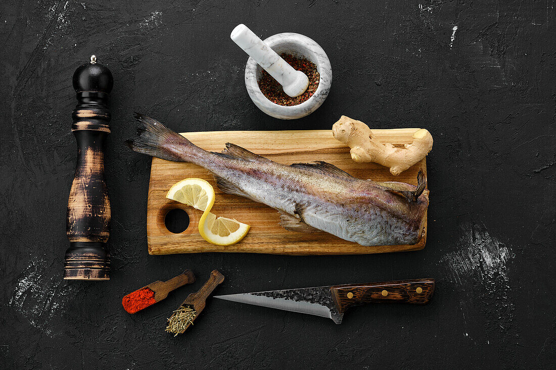 Raw frozen saithe on a wooden board with spices