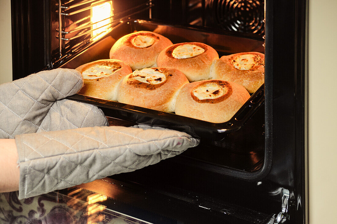 Frisch gebackene Brötchen aus dem Ofen nehmen