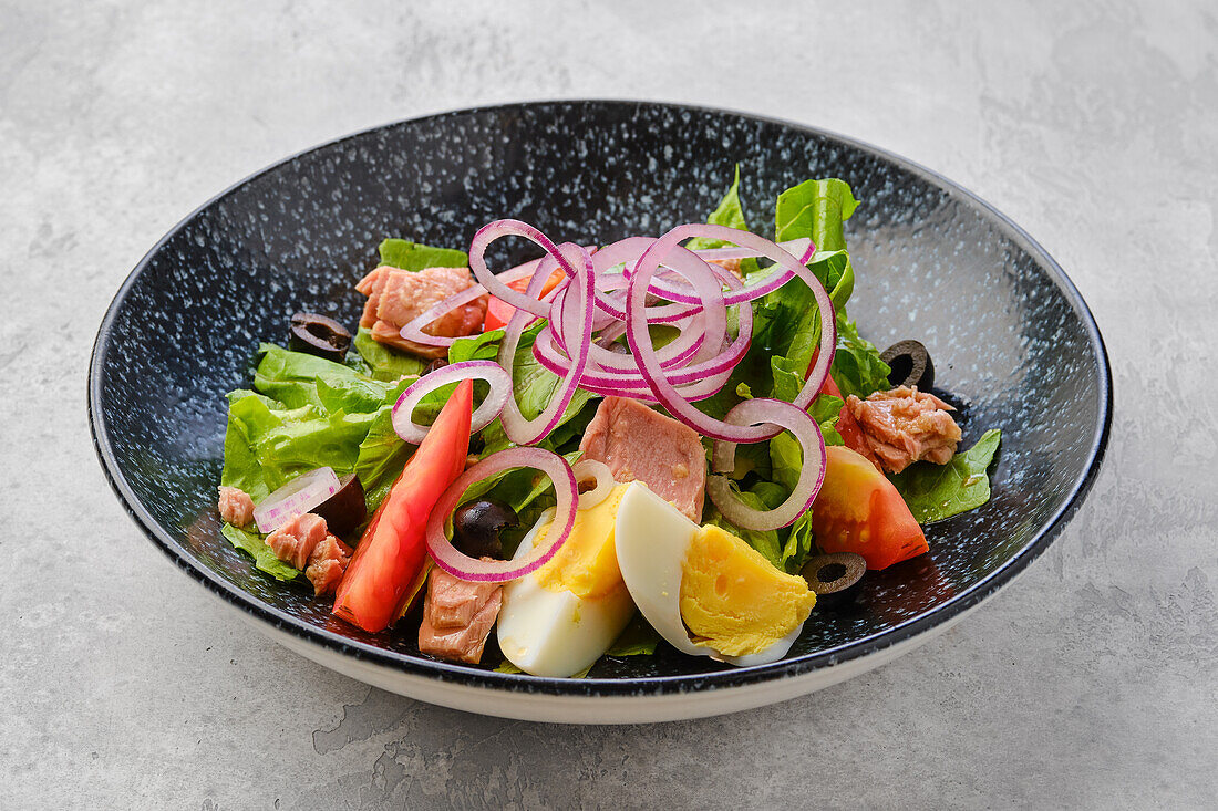 Salat mit Lachs, Ei, Tomate und roten Zwiebeln