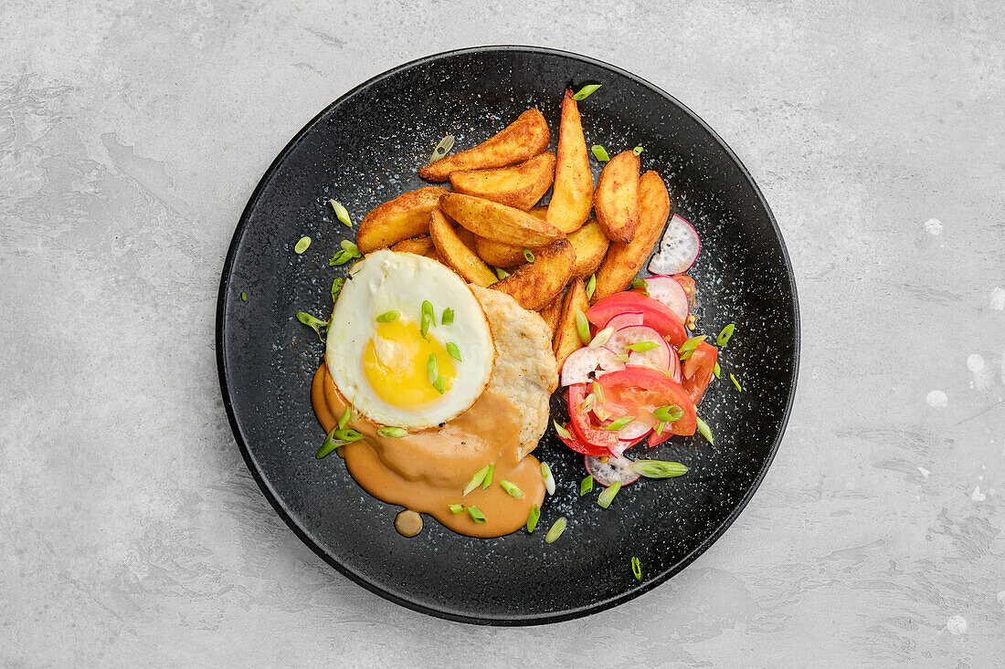 Pork steak with fried potatoes, fried egg and salad