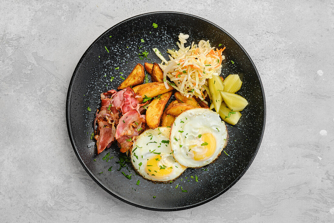 Fried eggs with bacon, potato wedges and coleslaw