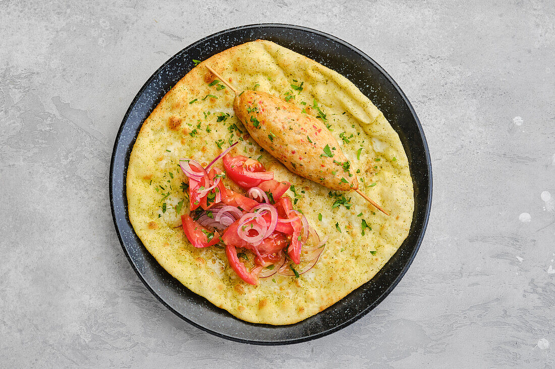 Kebab auf Tortilla mit Tomaten und roten Zwiebeln