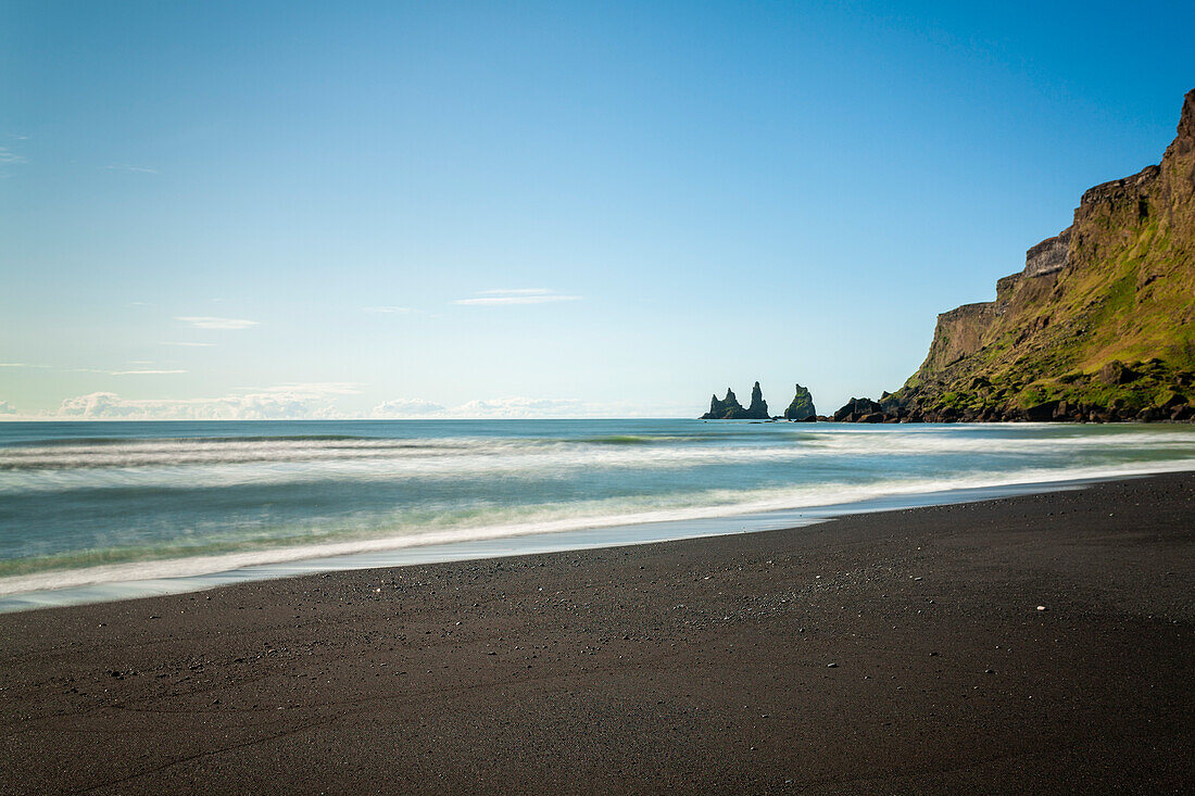 Schwarzer Sandstrand mit Reynisdrangar-Basaltfelsen und Klippen im Hintergrund, nahe Vik i Myrdal, Island