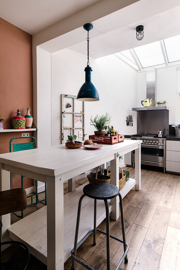 White kitchen with wooden floor and skylight, central kitchen island and pendant light