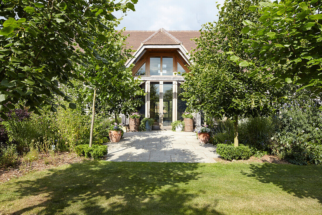 Blick vom Garten mit Rasen und Bäumen auf den Vordereingang