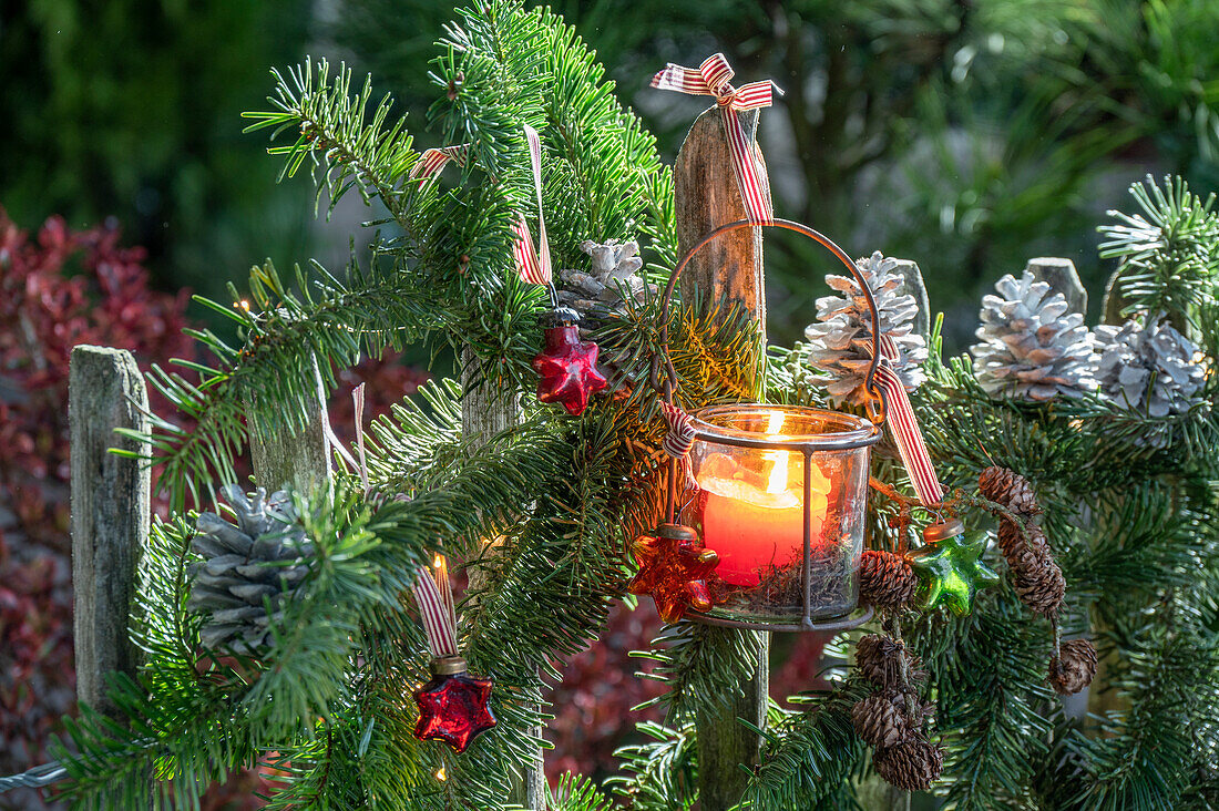 Adventsdeko am Gartenzaun mit Windlicht und Tannenzweigen