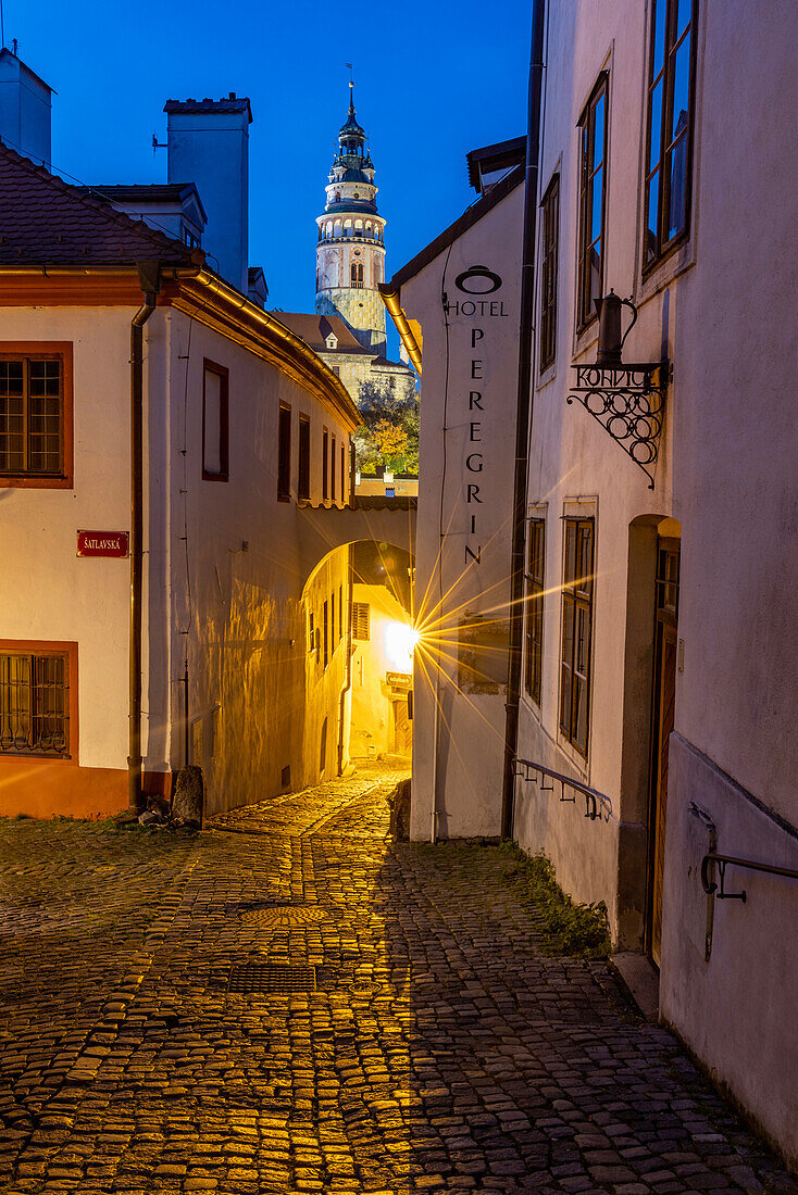 Enge Kopfsteinpflasterstraßen in der Abenddämmerung mit Schlossturm im historischen Cesky Krumlov, Tschechische Republik. (Nur für redaktionelle Zwecke)