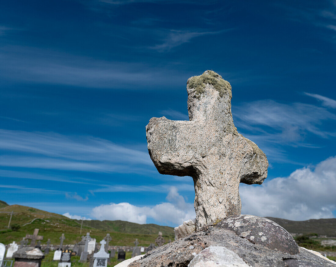 Ein abgenutztes Steinkreuz schmückt ein Grab in Kildavnet, Achill Island, County Mayo, Irland.