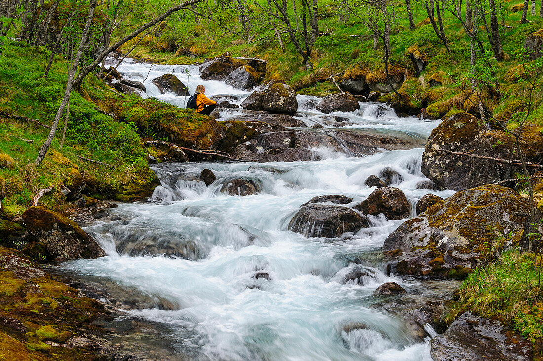 Norwegen, Nordland, Tysfjord. Frau sitzt am Storelva, dem Fluss, der aus dem Stetind (Norwegens Nationalberg) fließt. (MR)