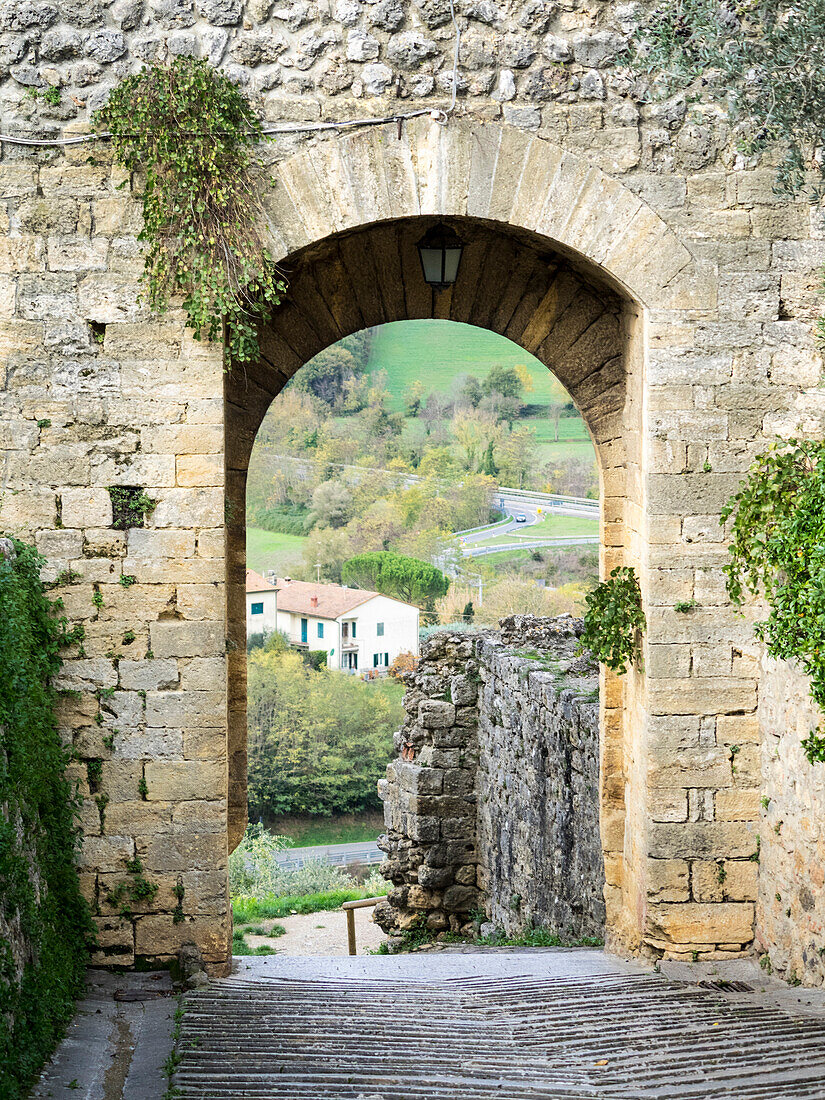 Italy, Chianti, Monteriggioni. Looking out an arched entrance into the walled town.