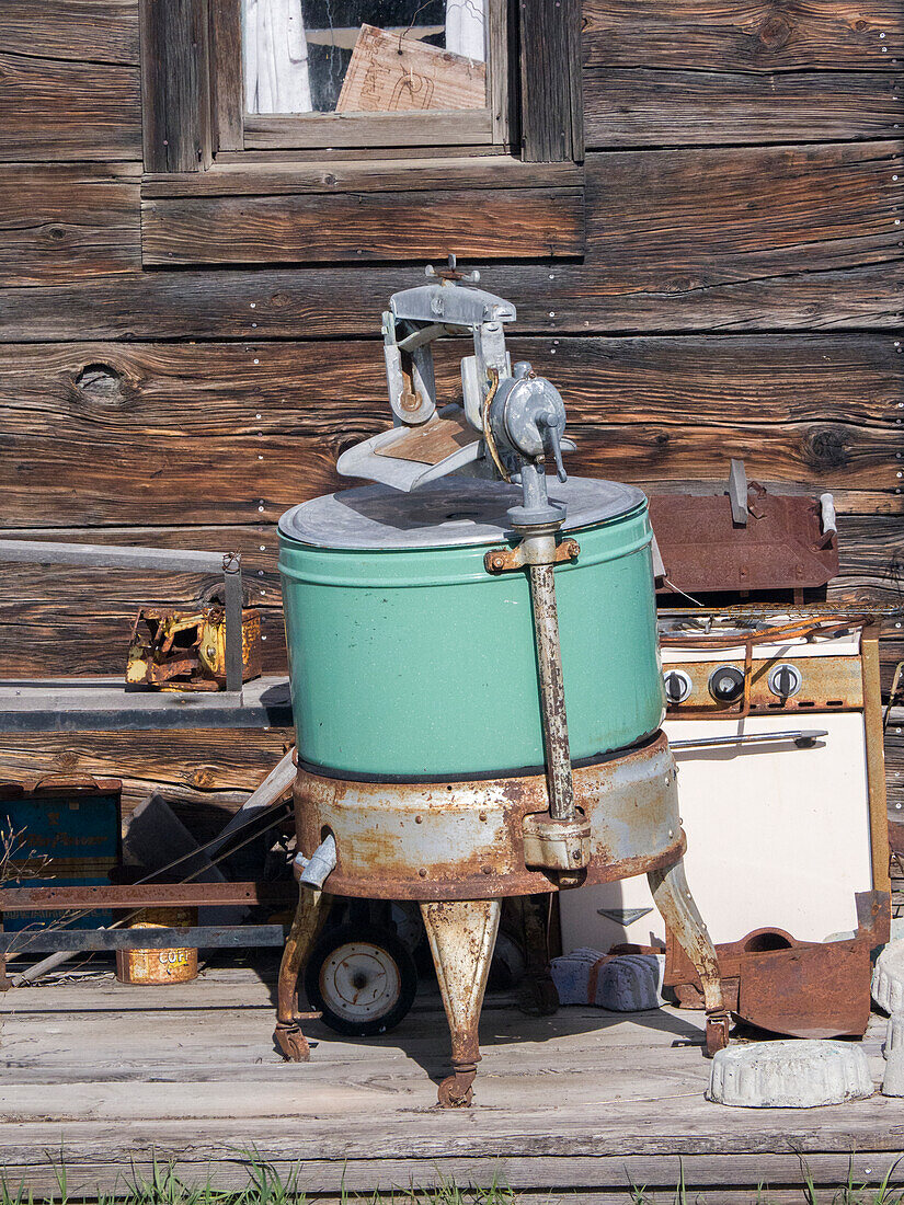 USA, Washington State, Molson, Okanogan County. An old washing machine and old rusty stove on the porch of a building in the historic ghost town.