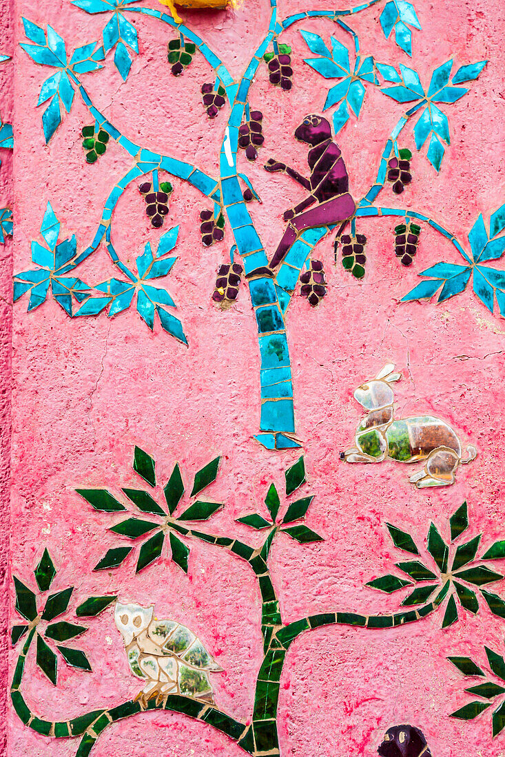 Laos, Luang Prabang. Mosaik-Wandmalerei, die einen Affen in einem Obstbaum darstellt.