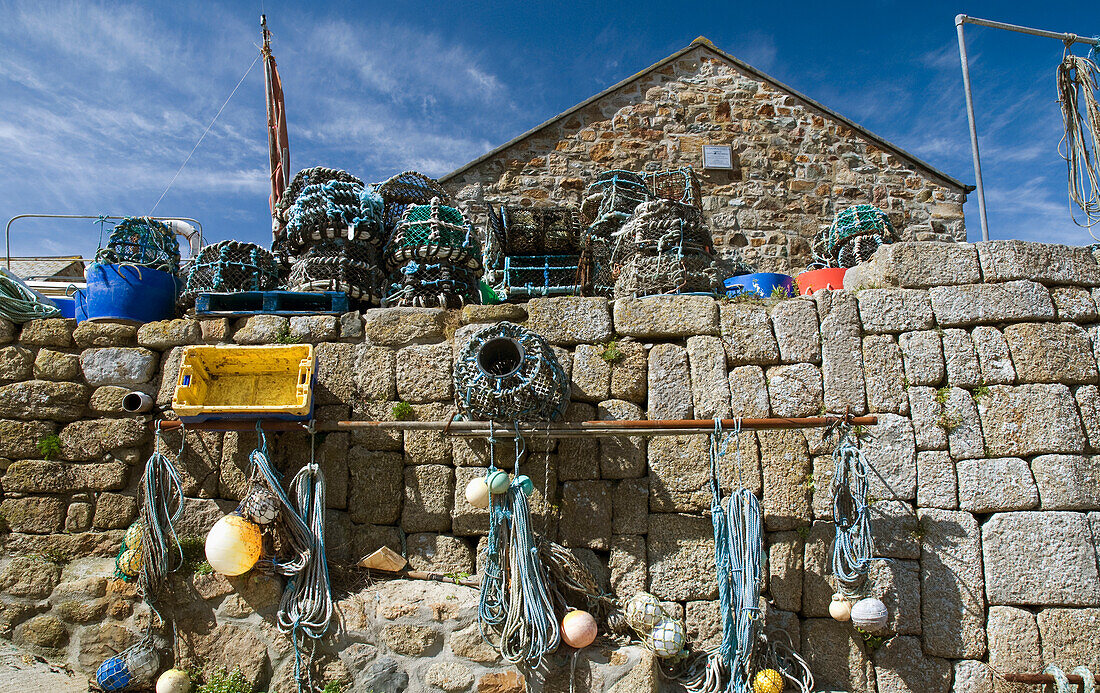 Fischernetze und Fallen an einer Steinmauer