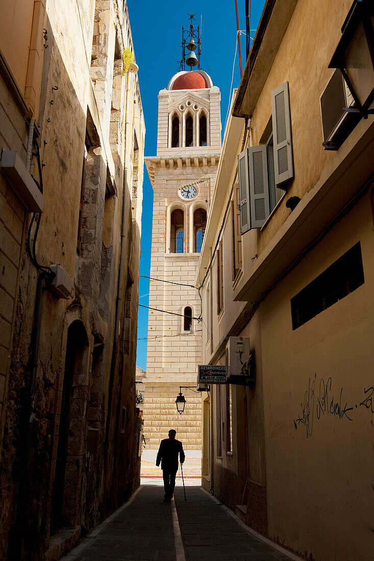 Greece, Crete, Man Walking Down Narrow Alley to Church; Rethymno