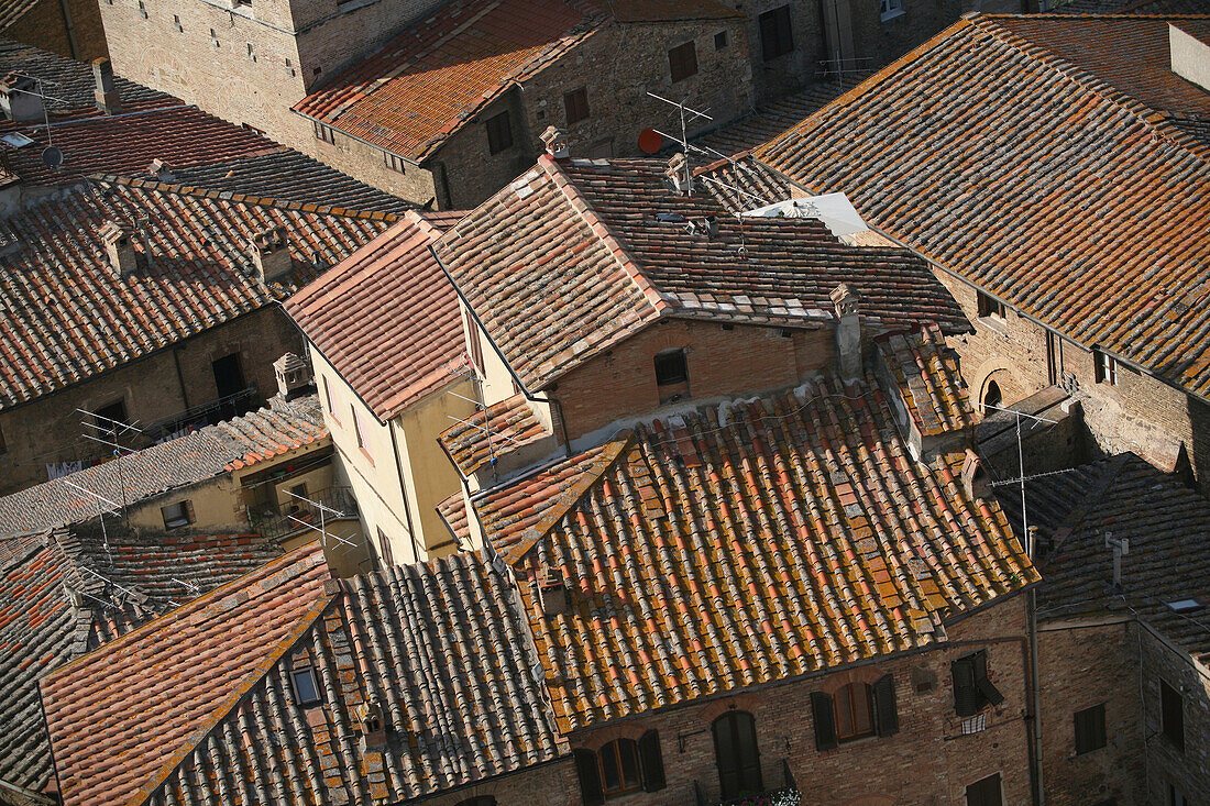Geflieste Dächer von einem alten Turm im Zentrum von San Gimignano aus gesehen, einer berühmten mittelalterlichen Stadt auf einem Hügel; San Gimignano, Toskana, Italien