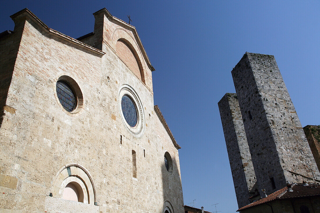 Kirche und zwei der Türme von San Gimignano, einer berühmten mittelalterlichen Hügelstadt mit alten Türmen, in der Toskana. Italien. Juni.