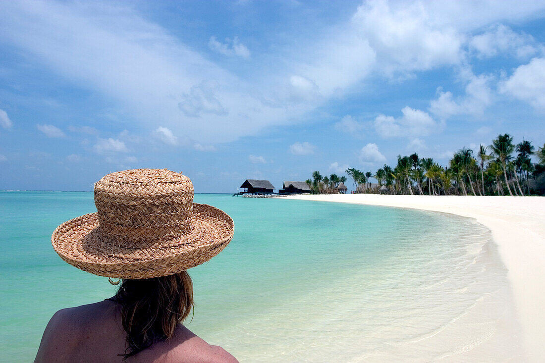 Eine Frau spaziert an einem weißen Sandstrand; Malediven