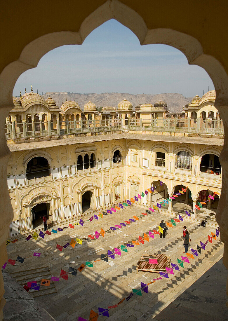 Kite art installation during former Jaipur Heritage Festival, viewed through scalloped arch at Ramchandraji Temple, Jaipur, Rajasthan, India, Jaipur, Rajasthan, India.