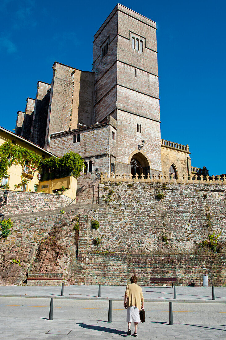 Frau geht vor der Pfarrkirche St. Peter, Zumaia, Baskenland, Spanien