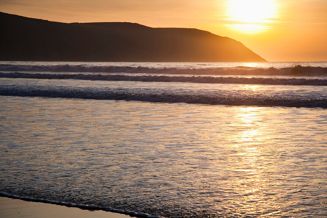 Sonnenuntergang über dem Meer und Strand in Putsborough Sands, Nord-Devon, Großbritannien