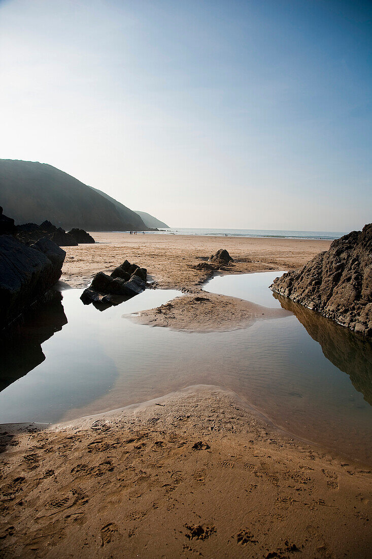 Großer Felsentümpel am Strand umgeben von Felsen in Putsborough Sands, Nord-Devon, Großbritannien