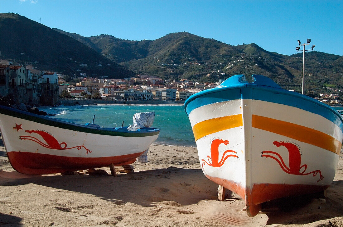 Sizilien, Italien: Mit traditionellen Seepferdchen-Motiven geschmückte Boote am kleinen Strand im Hafen der Altstadt von Cefalu. Copyright.