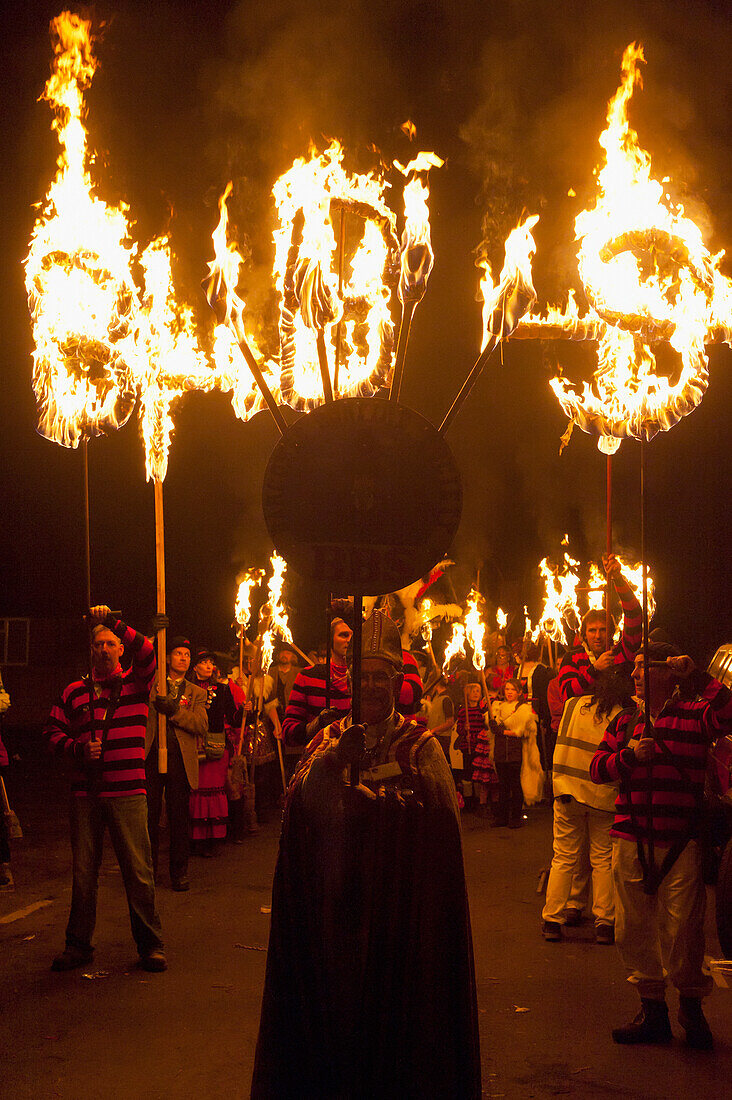 Man Dressed As Bishop In Front Of People With Burning Banners At Head Of Procession At Barcombe Bonfire Night, Barcombe, East Sussex, Uk