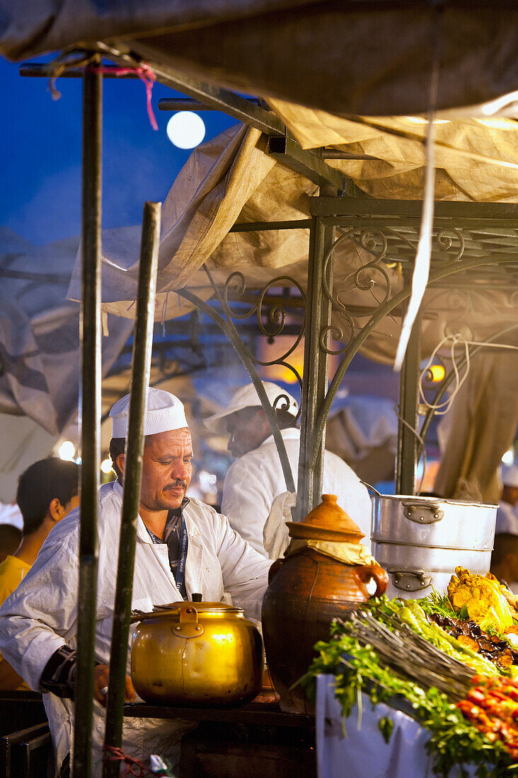 Morocco, Cook serving food at stall in Djemaa el-Fna Square; Marrakech