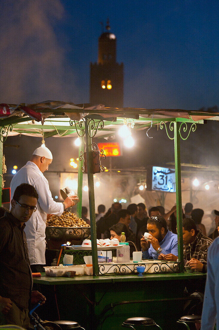 Morocco, Cook serving food at stall in Djemaa el-Fna Square; Marrakech