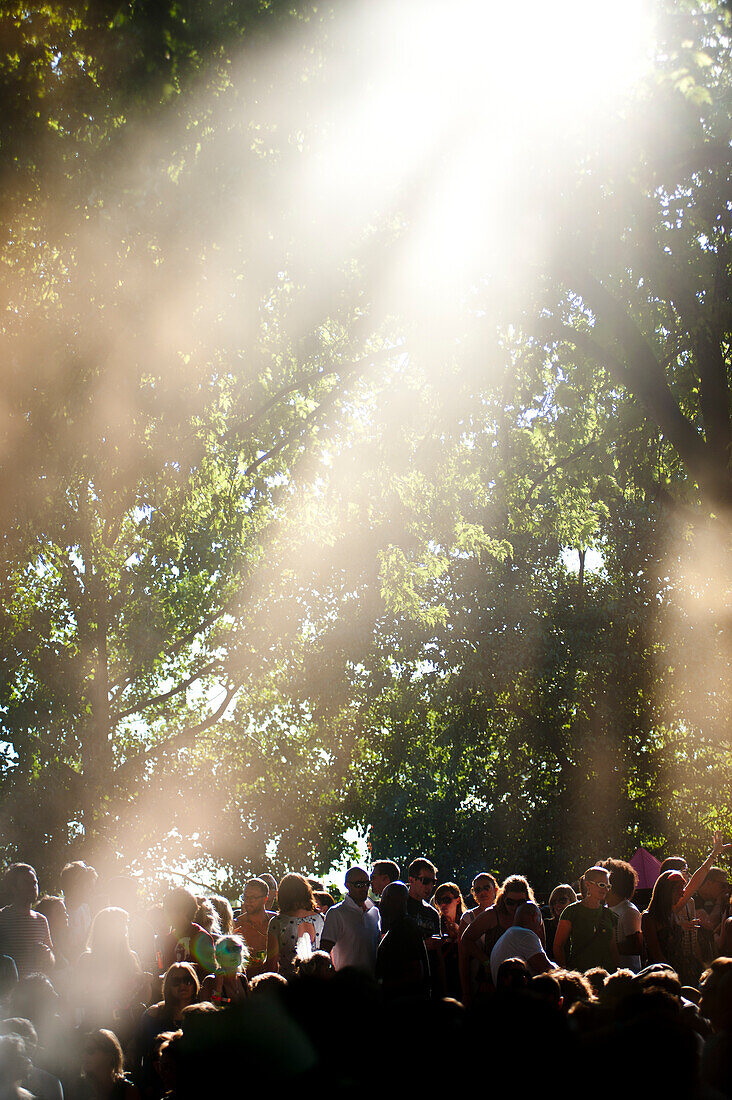 Sonnenstrahlen, die durch die Bäume über die Clubber beim Lovebox Festival im Victoria Park, London, Großbritannien fallen
