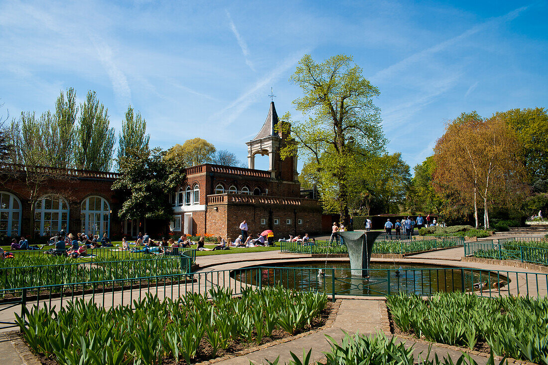 Menschen beim Sonnenbaden an einem Frühlingstag im Holland Park, West London, London, Großbritannien