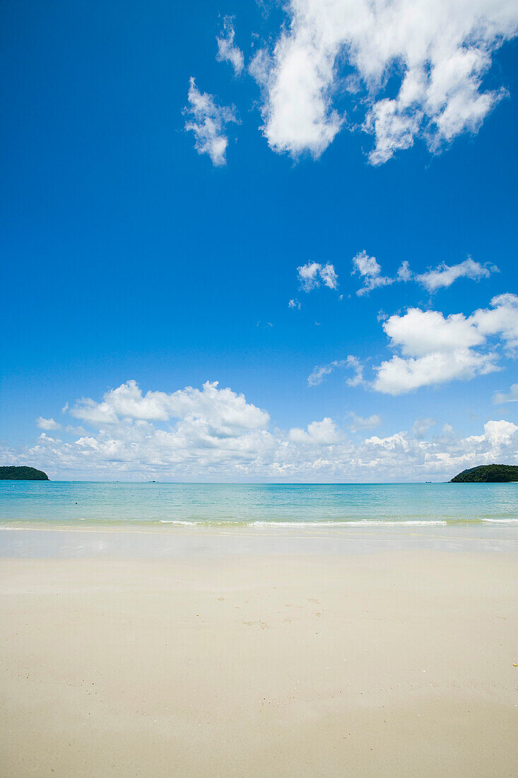 Malaysia, Pantai Cenang (Cenang Strand); Pulau Langkawi, Inseln im Hintergrund, weite Sicht auf weißen Sandstrand und blauen Himmel